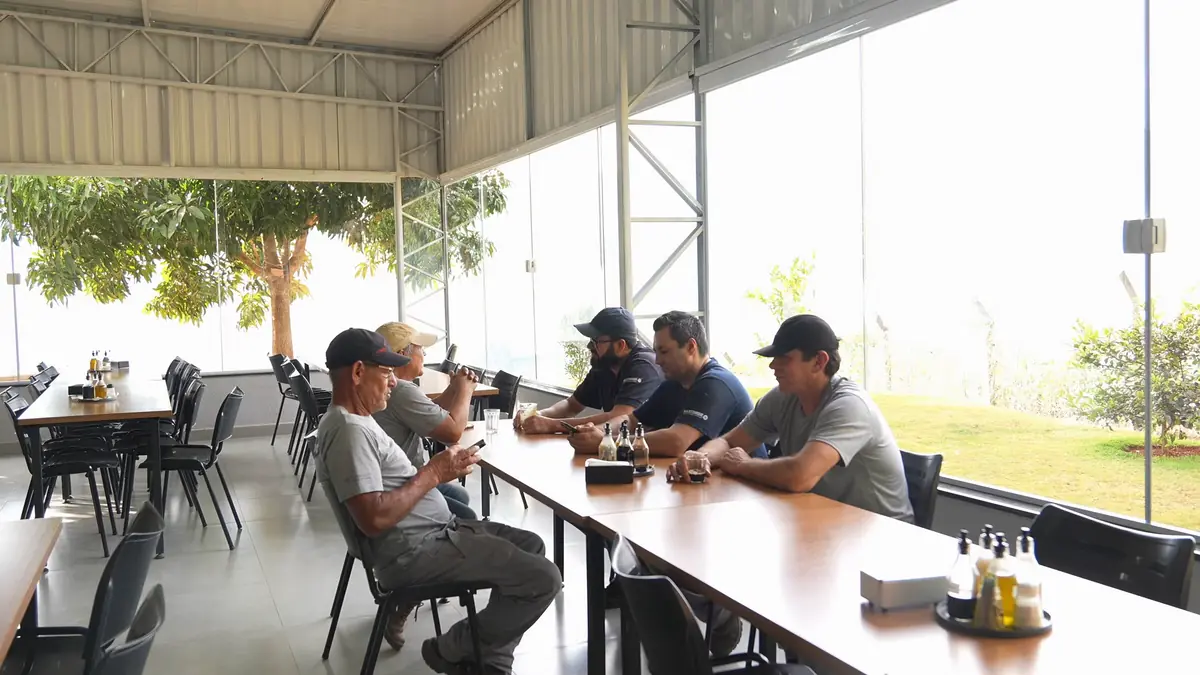 Colaboradores da Lineaplas reunidos na área de convivência da fábrica, com vista para o jardim