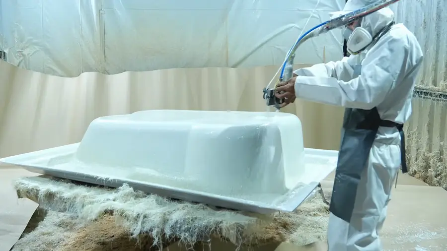 Aplicação de gel coat por pulverização em uma peça na fábrica da Lineaplas, feita por colaborador com equipamento de proteção